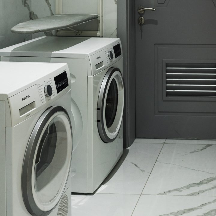 Two washing machines in a room with white tiled flooring
